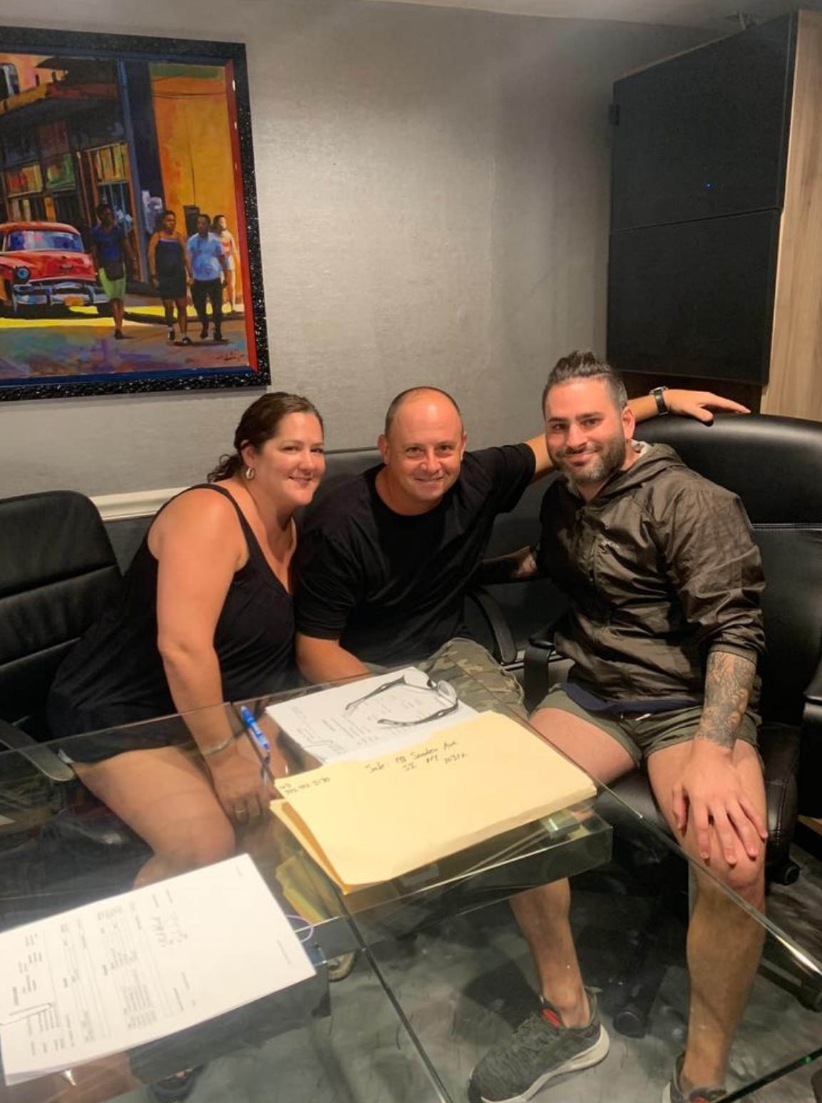 Three people (two men, one woman) sitting at an office table, smiling